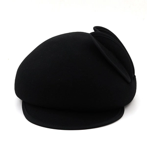 Close-up of black wool beret detailing the side decorative wing embellishment