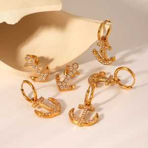 Detailed view of gold anchor earrings with sparkling cubic zirconia on a stone tray