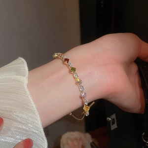 Close-up of a colorful zircon bracelet with square and teardrop stones on a gold chain
