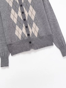 Detailed view of grey argyle knit cardigan with dark buttons and ribbed cuffs