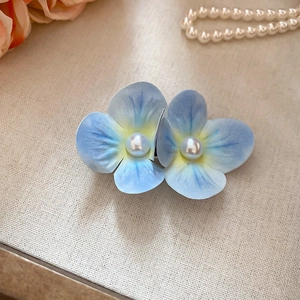 Detail shot of elegant blue floral hair clip with pearl center on linen background