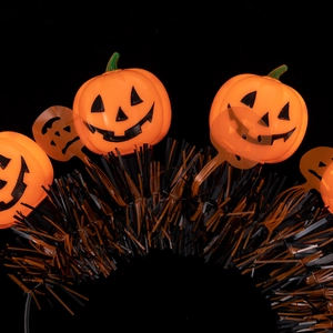 Close-up of Halloween headband featuring orange pumpkin faces and shiny metallic tinsel