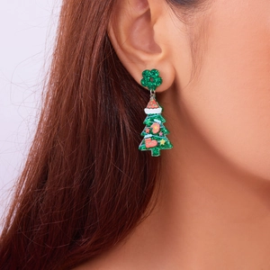 Close-up of green glitter Christmas tree earrings with festive red and white details