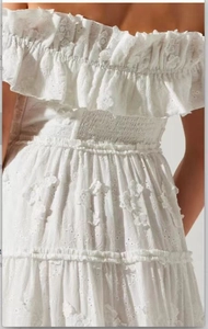 Detail of off-shoulder dress with layered ruffles and intricate floral embroidery texture