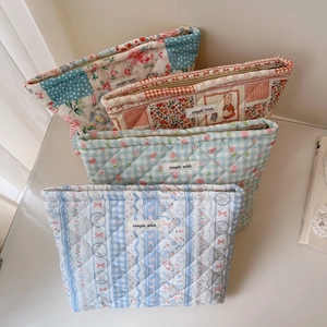 Close-up of four quilted cotton makeup bags with floral and checkered patterns