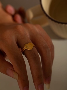 Detail of a gold heart ring featuring Love You engraving and a textured band on hand