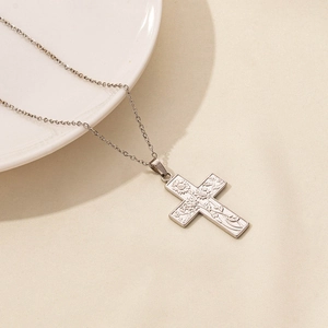 Detailed macro shot of silver stainless steel cross pendant with engraved sunflower