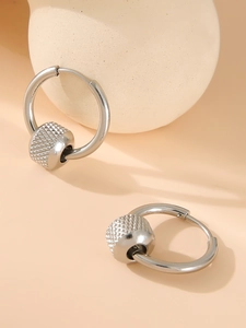 Detail of silver stainless steel hoop earrings with textured diamond-cut metal beads