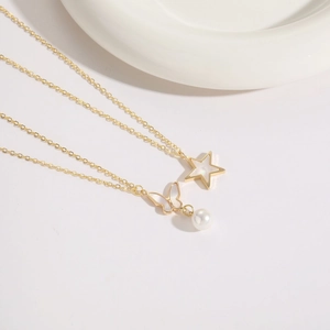 Vue macro détaillée du pendentif étoile et papillon plaqué or 14K avec perle blanche