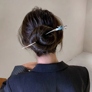 Detailed view of a silver bamboo-shaped hair pin styled in a low bun hairstyle
