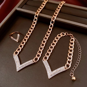 Macro view of rose gold jewelry set including necklace, bracelet and ring with V-shaped diamonds