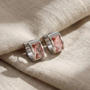 Detailed macro view of silver hoop earrings featuring rectangle pink crystal gemstones