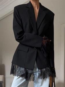Close-up detail of delicate black lace hem and sleeve cuffs on a slim fit suit jacket
