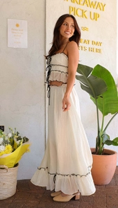 Detail of cream ruffled top and pleated maxi skirt with black contrast piping edges