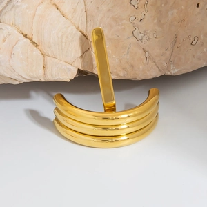 Macro view of tiered 18K gold plated U-shaped cuff bracelet on a natural stone surface