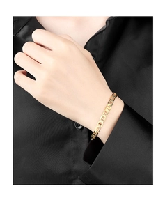Classic 18K gold plated flat link chain bracelet worn on a wrist over black fabric
