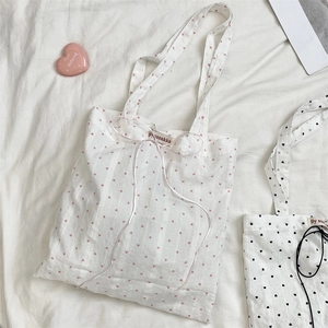Detail of white canvas tote bag with red heart print and ribbon tie decoration