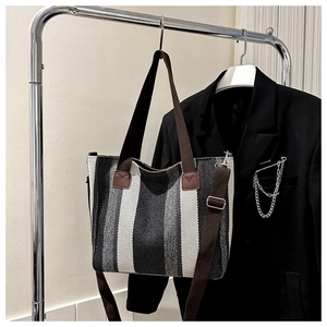 Close-up of striped canvas tote bag with woven handles and adjustable shoulder strap