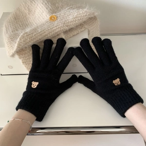 Close-up of black knitted gloves featuring small brown bear embroidery on the ribbed cuff