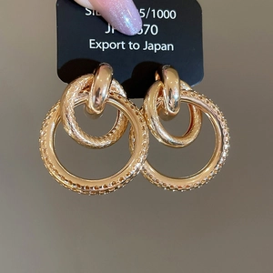 Macro de boucles d'oreilles doubles anneaux dorés avec texture en treillis et fini poli