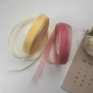 Detail view of 2cm sheer organza ribbons in pale yellow and dusty pink for gift wrapping