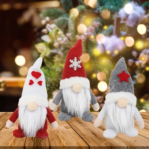 Three Christmas gnomes in red, white and grey plush standing on a wooden festive table