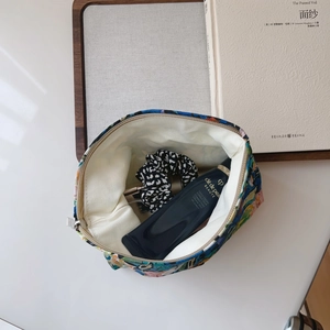 Floral canvas makeup bag with silver zipper showing interior lining and hair accessories