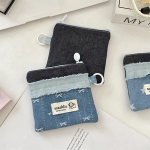 Detail der Patchwork-Geldbörse aus Denim mit weißem Schleifendruck und Hunde-Aufnäher