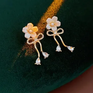 Boucles d'oreilles élégantes à fleurs et nœuds avec longs pompons sur fond velours
