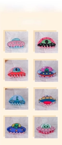 Detail showcasing eight colorful UFO-shaped PVC hair claws with diverse alien patterns