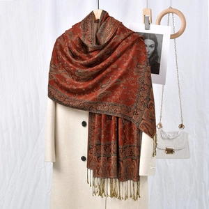 Close-up of reddish-brown paisley scarf with tassel trim on beige coat