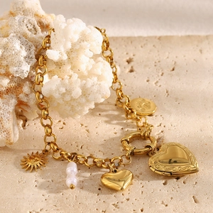 Detailed view of 18K gold plated heart locket bracelet draped over white coral branch