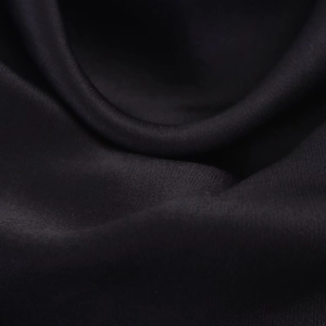 Macro shot of high-quality black satin fabric showing silky texture and elegant draping