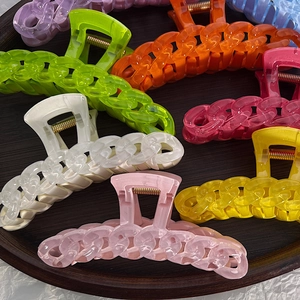 Detailed view of colorful acrylic chain-style hair claws in a round wooden tray