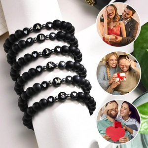 Gros plan de bracelets en perles noires mates avec lettres et breloques en cœur