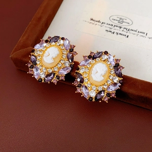Macro shot of vintage cameo earrings with purple rhinestones on a brown leather base