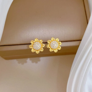 Golden sunflower earrings with clear zircon crystals on brown display case