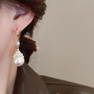 Gros plan de boucles d'oreilles dorées avec perles et zircons portées par un mannequin