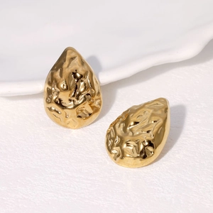 Boucles d'oreilles goutte dorées avec texture martelée sur fond blanc propre