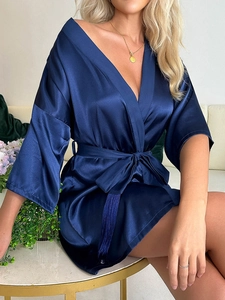 Détail d'un peignoir en satin bleu marine avec manches larges et ceinture à la taille