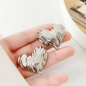 Close-up of S925 silver heart earrings with textured metallic stripes and silver finish