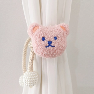 Detail of pink plush bear curtain tieback with white pearl pendants on fabric