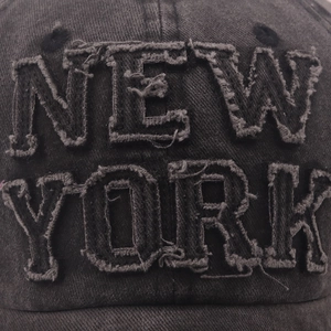 Macro shot of vintage washed denim baseball cap with frayed New York 3D embroidery detail
