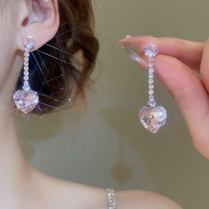 Detail of sparkling zircon heart earrings with long tassels on a model and hand