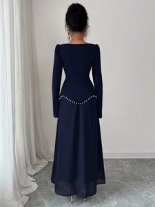 Détail de robe de soirée bleu foncé avec dos en V orné de perles et manches bouffantes