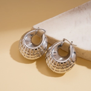 Close-up of silver geometric C-shape earrings with grid texture on white marble stone