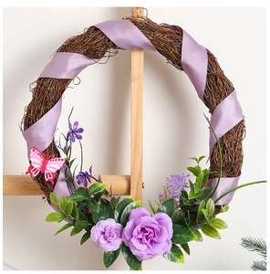 Close-up of purple silk flowers and ribbon bow on decorative dry rattan Christmas wreath