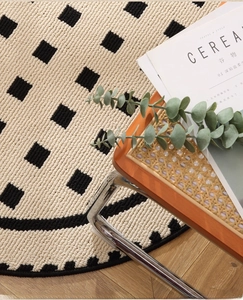 Detail of round cream rug with black geometric patterns on a wooden floor