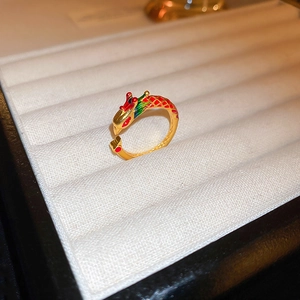 Detailed close-up of a golden dragon ring with colorful enamel inlay on a velvet tray