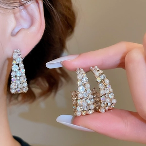 Detail of elegant C-shaped earrings featuring luxury pearls and sparkling rhinestones